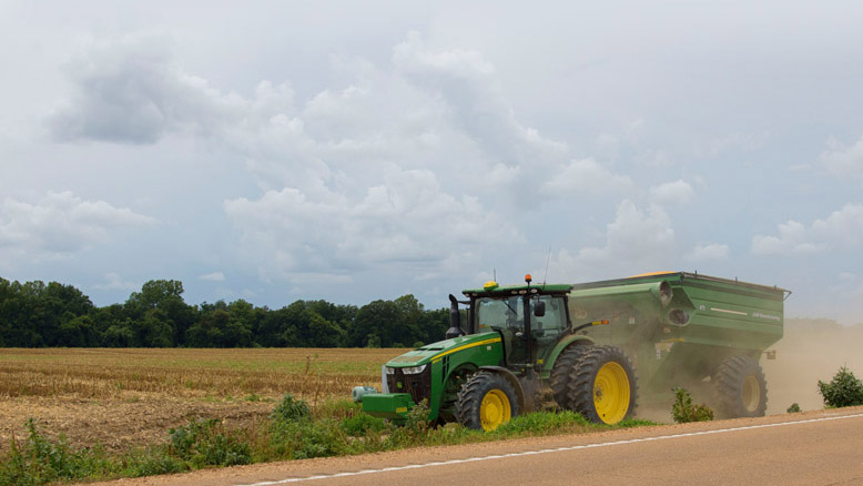A tractor drives beside a crop