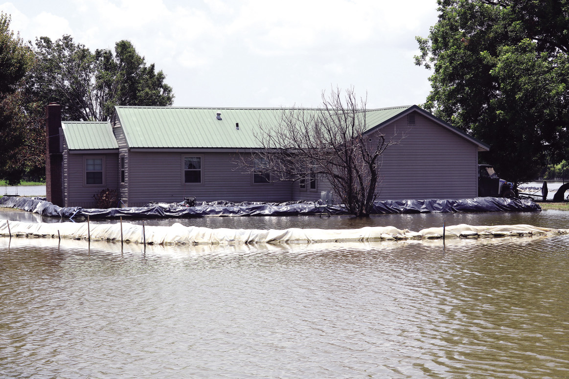 A house has one barrier near its foundation and another barrier farther out away to protect it from the flood.
