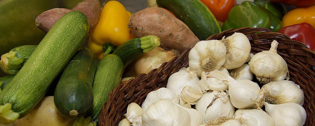 This is an image of different foods, potato, garlic, peppers, and zuchinni