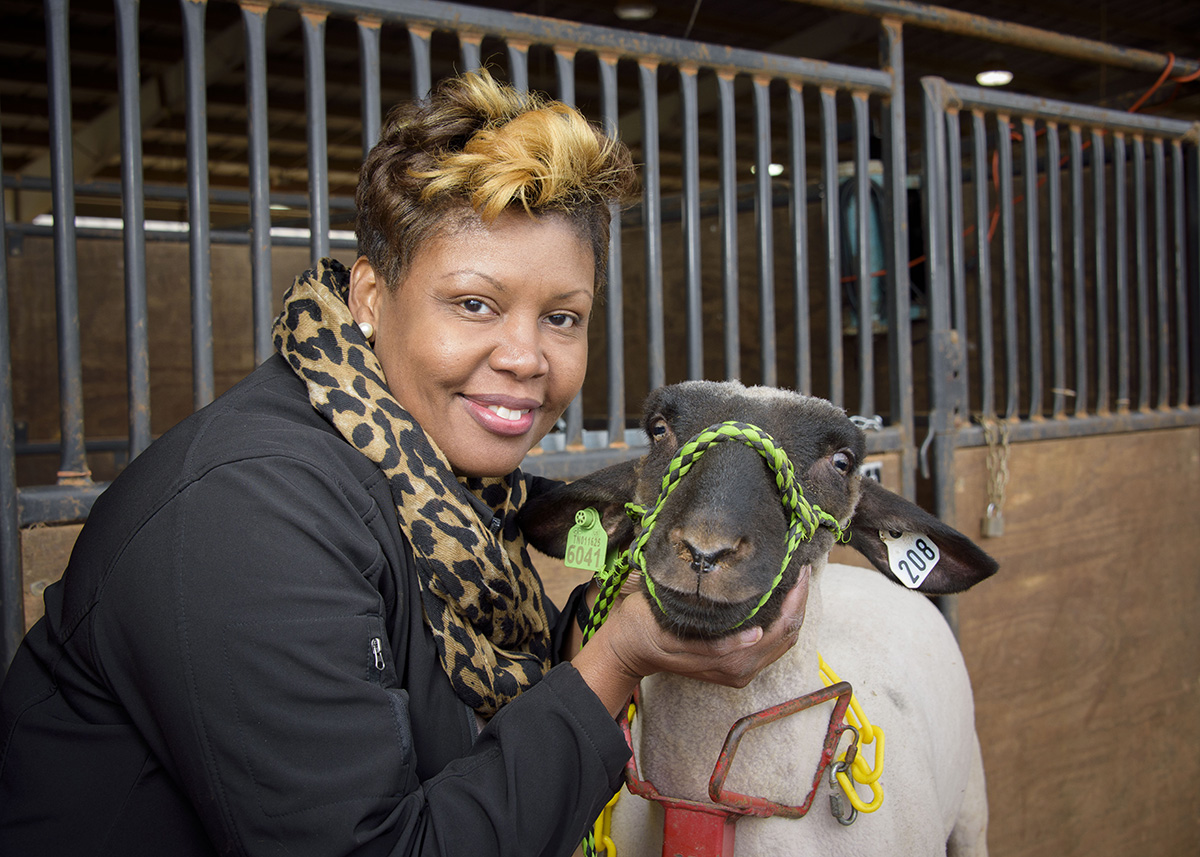 : Extension agent poses cheerfully with a goat during a local 4-H livestock show