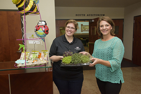 Two Extension instructors hold a tray of microgreens.