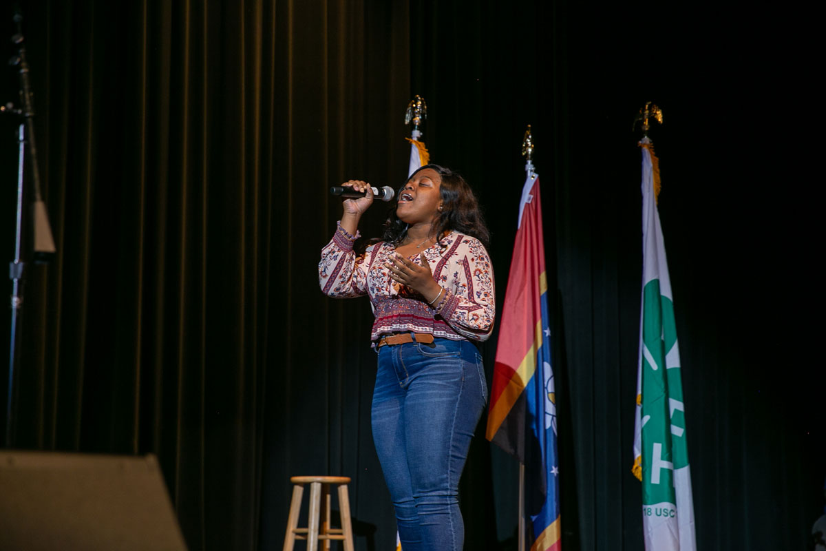 A teenage girl singing into a microphone.