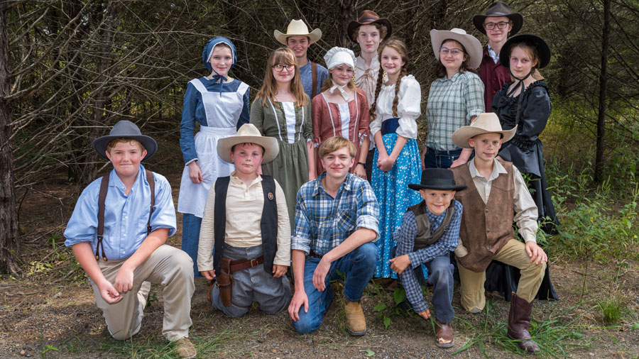Children smiling and dressed in old western-style apparel