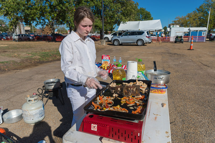 A girl cooking on an outdoor grill.