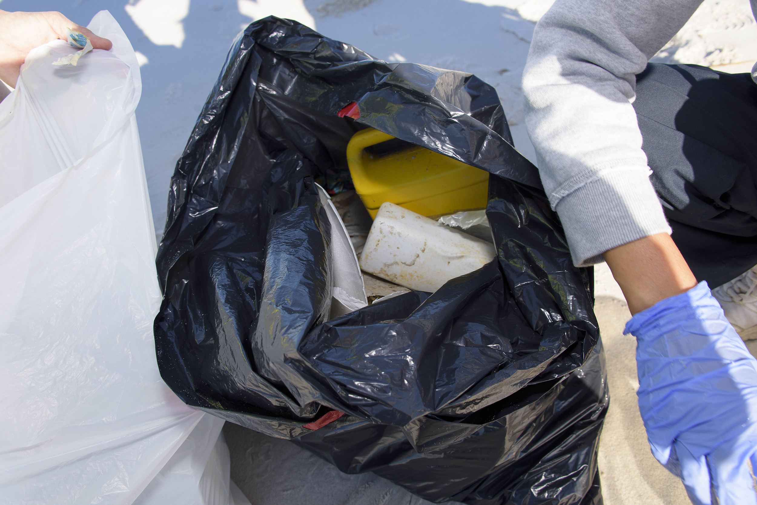 Plastic debris is seen in an open black trash bag sitting on the beach at the 2016 Mississippi Coastal Cleanup.