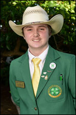 A boy wearing a cowboy hat and green jacket, smiling.
