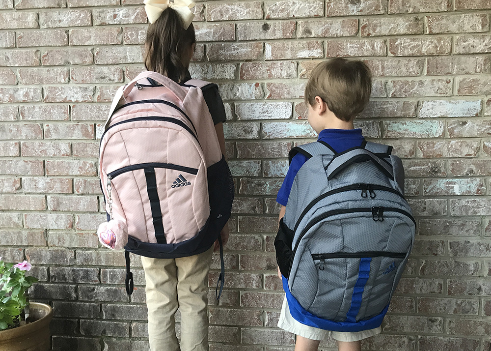 Two children wear backpacks to demonstrate the proper fit.