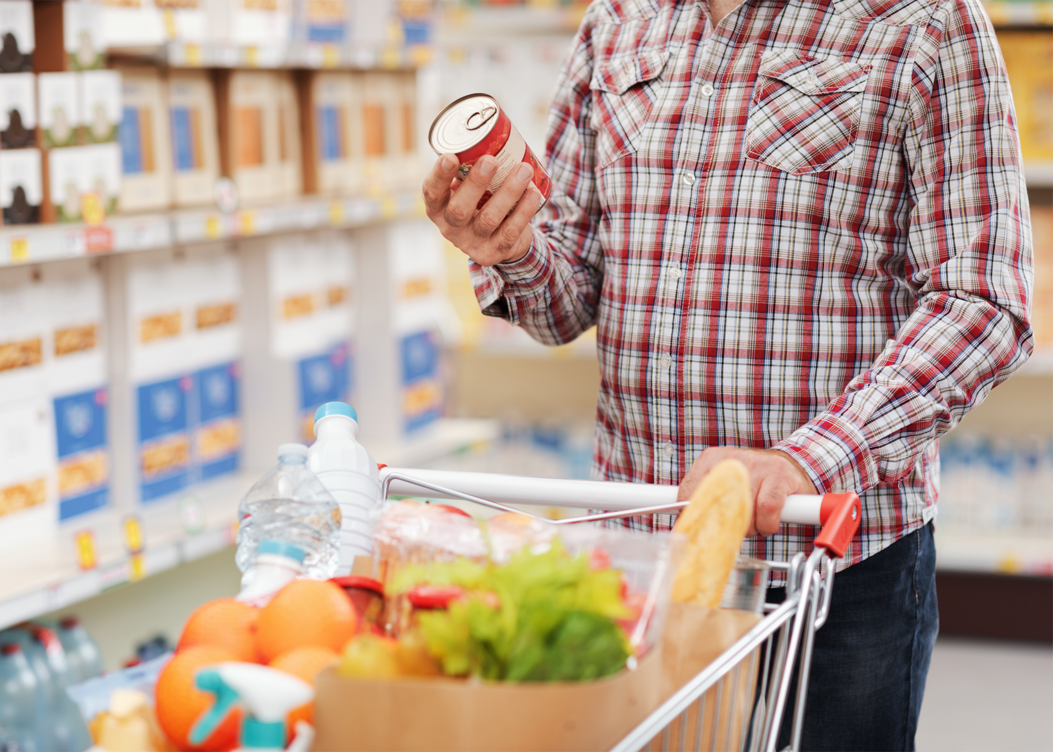 A person reads a Nutrition Facts label on a can of food in the grocery store.