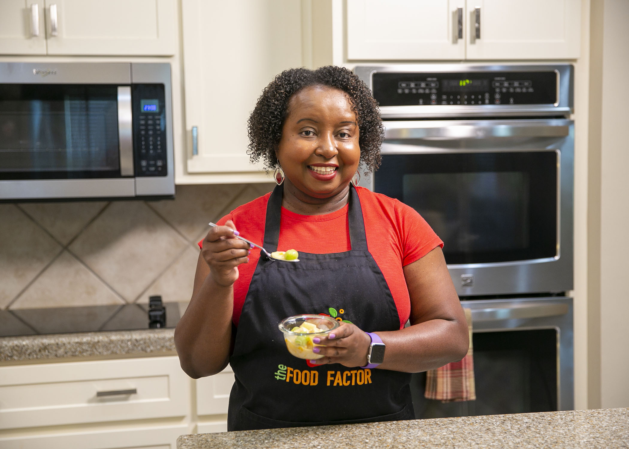 A woman stands in a kitchen with a bowl of Fruit Paradise
