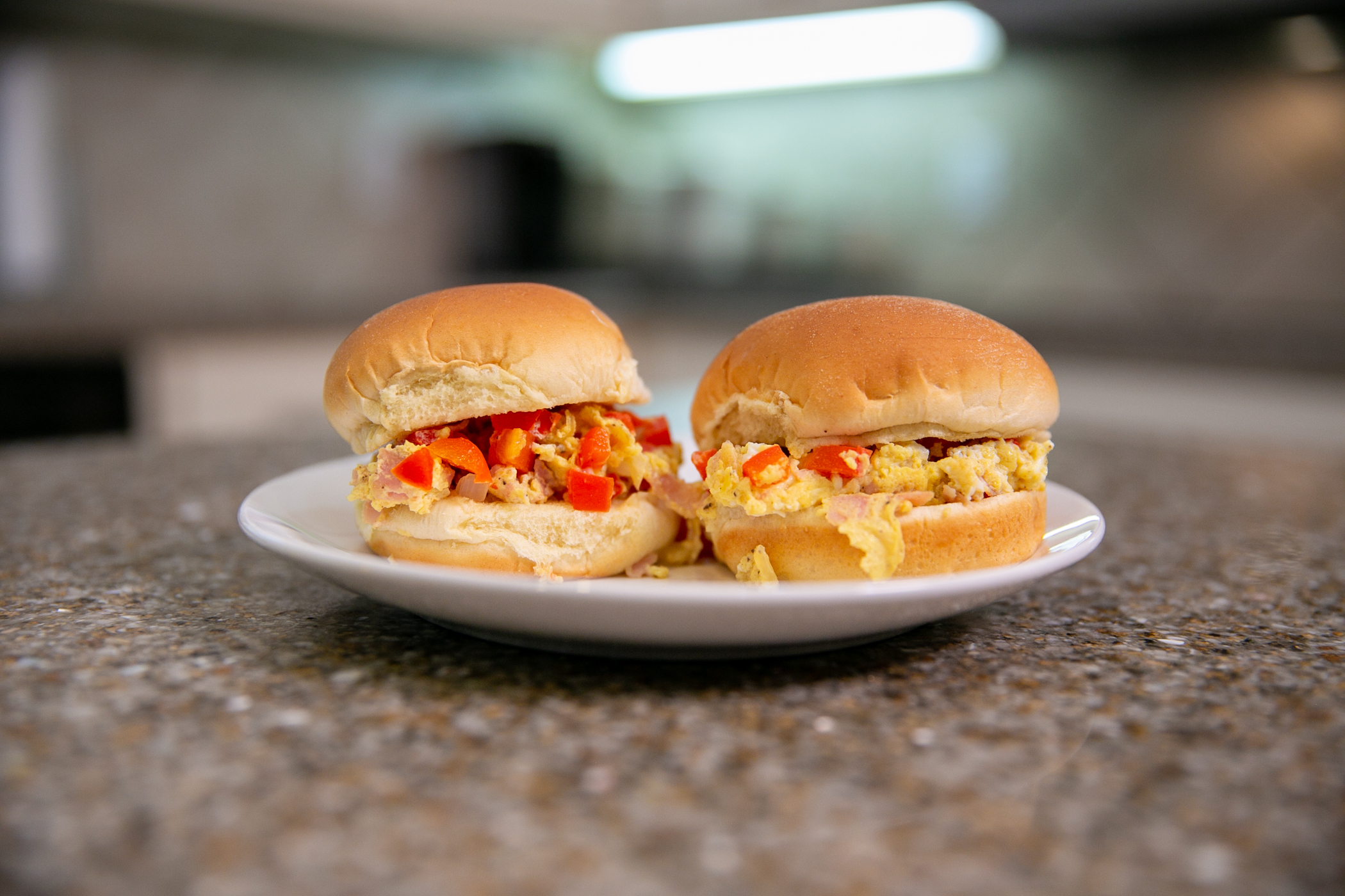 Two Microwave Denver Scramble Sliders sit on a plate on a kitchen countertop.