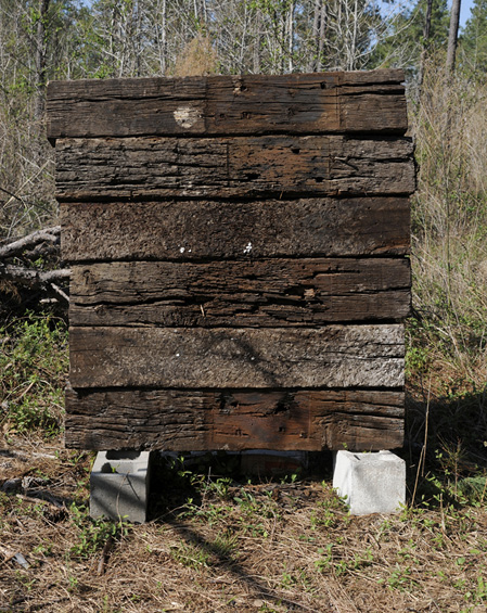 Six railroad crossties stacked on two cinder blocks in the woods.