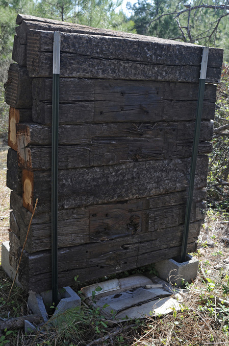 A completed backstop, six crossties high, on cinderblocks with T-posts on either end.