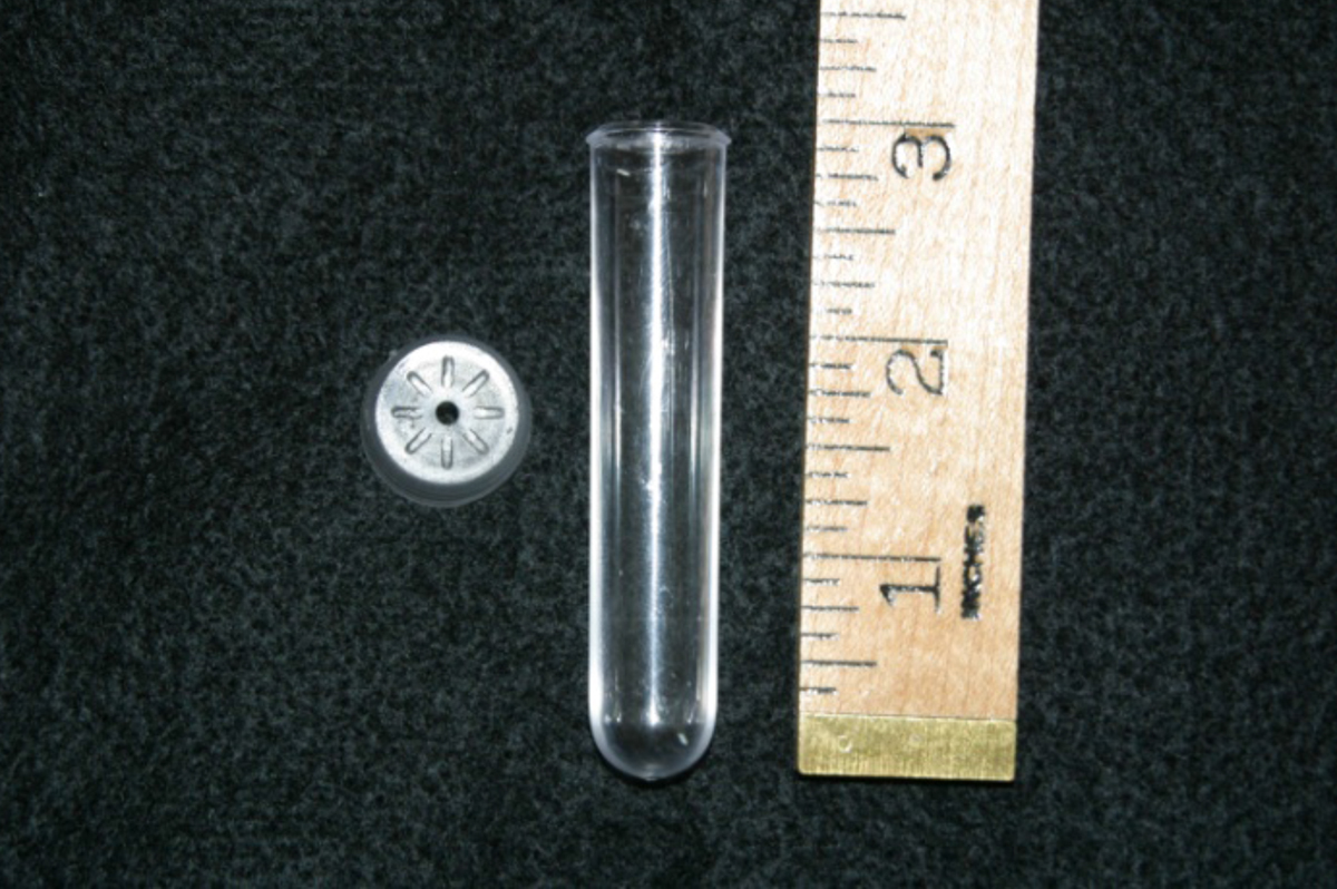 A plastic tube next to a ruler showing the tube measures 3 inches tall.