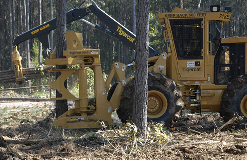 A large piece of equipment removes a tree trunk.