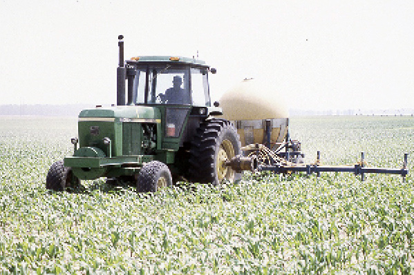 A tractor pulling a fertilizer container over crops.