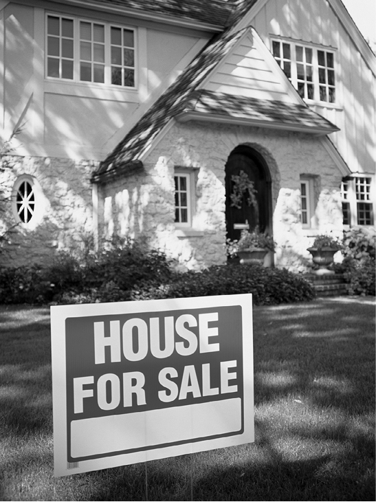 Image of a house with a for sale sign in the yard.