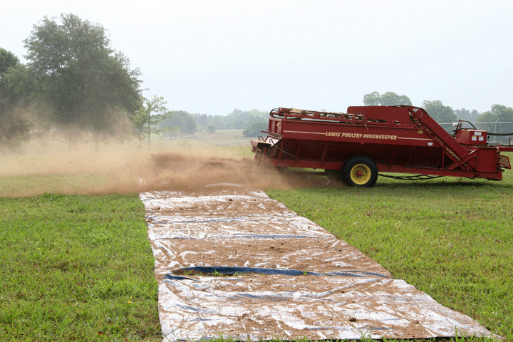 Image of a spreader spreading litter over a tarp, demonstrating the second part of step 4