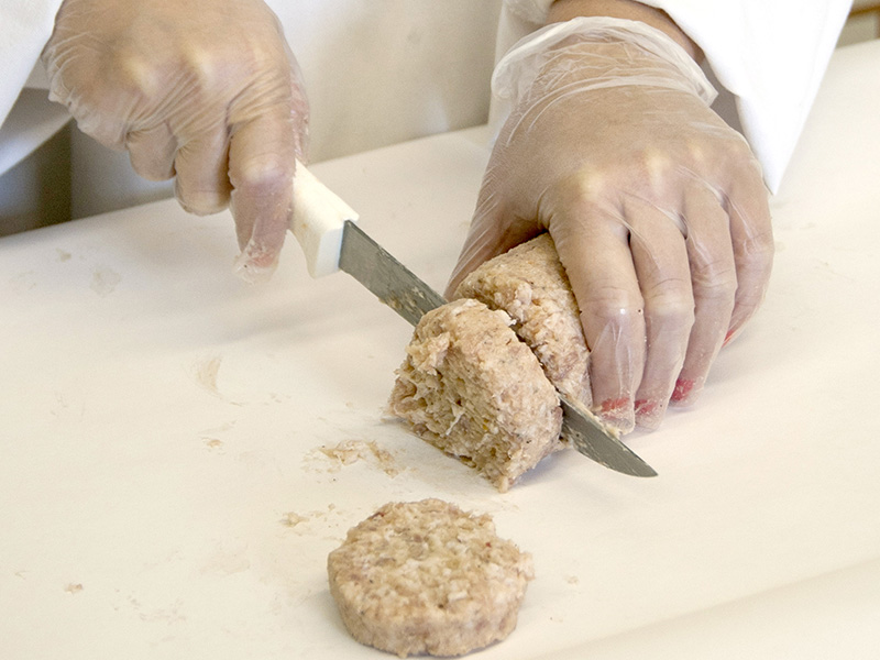 An image of someone sliding fresh pork sausage.