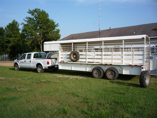 A clean white trailer pulled by a white truck. 