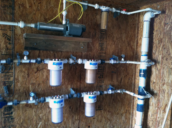 A 4-inch supply line from the well with 1-inch distribution lines to the drinkers in the front and back halves of the house and to the cooling system.