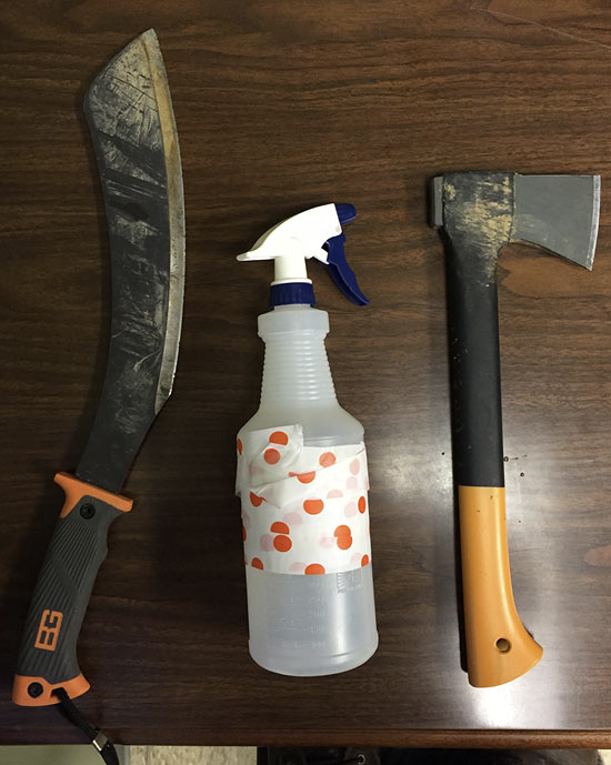 A small machete, a spray bottle, and a hatchet/hand ax are displayed on a table.