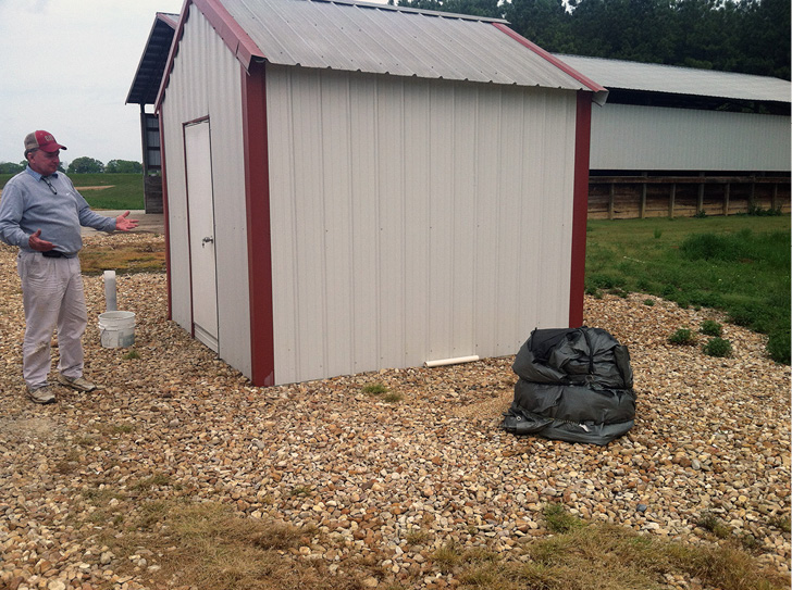 A small well house made of silver metal siding. 
