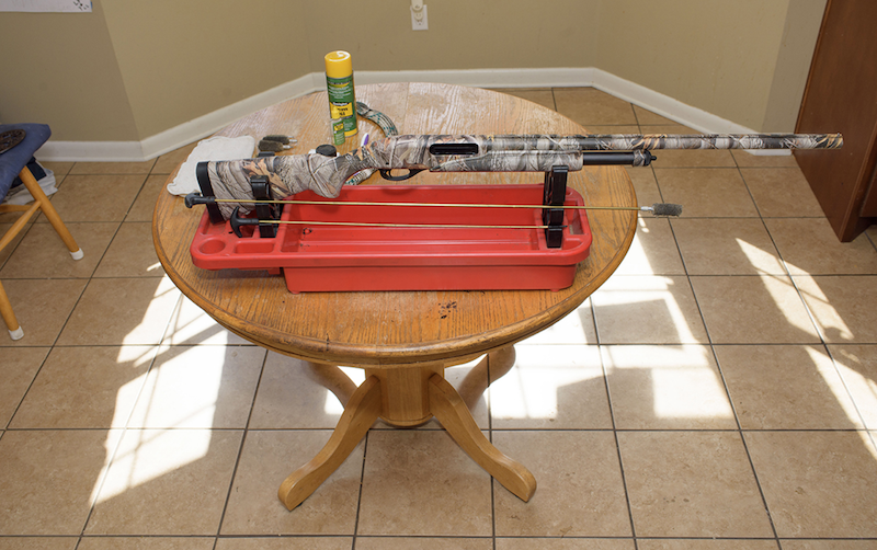 A standard hunting rifle is displyed on a coffee table in preparation for cleaning.