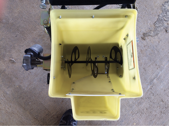 Yellow broadcast spreader with a mechanism with three blades running through the center. These blades are spaced out and have holes.