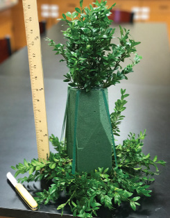 Foam brick with greenery attached at the top and base. A ruler standing next to the brick shows the overall height of about 16 inches.