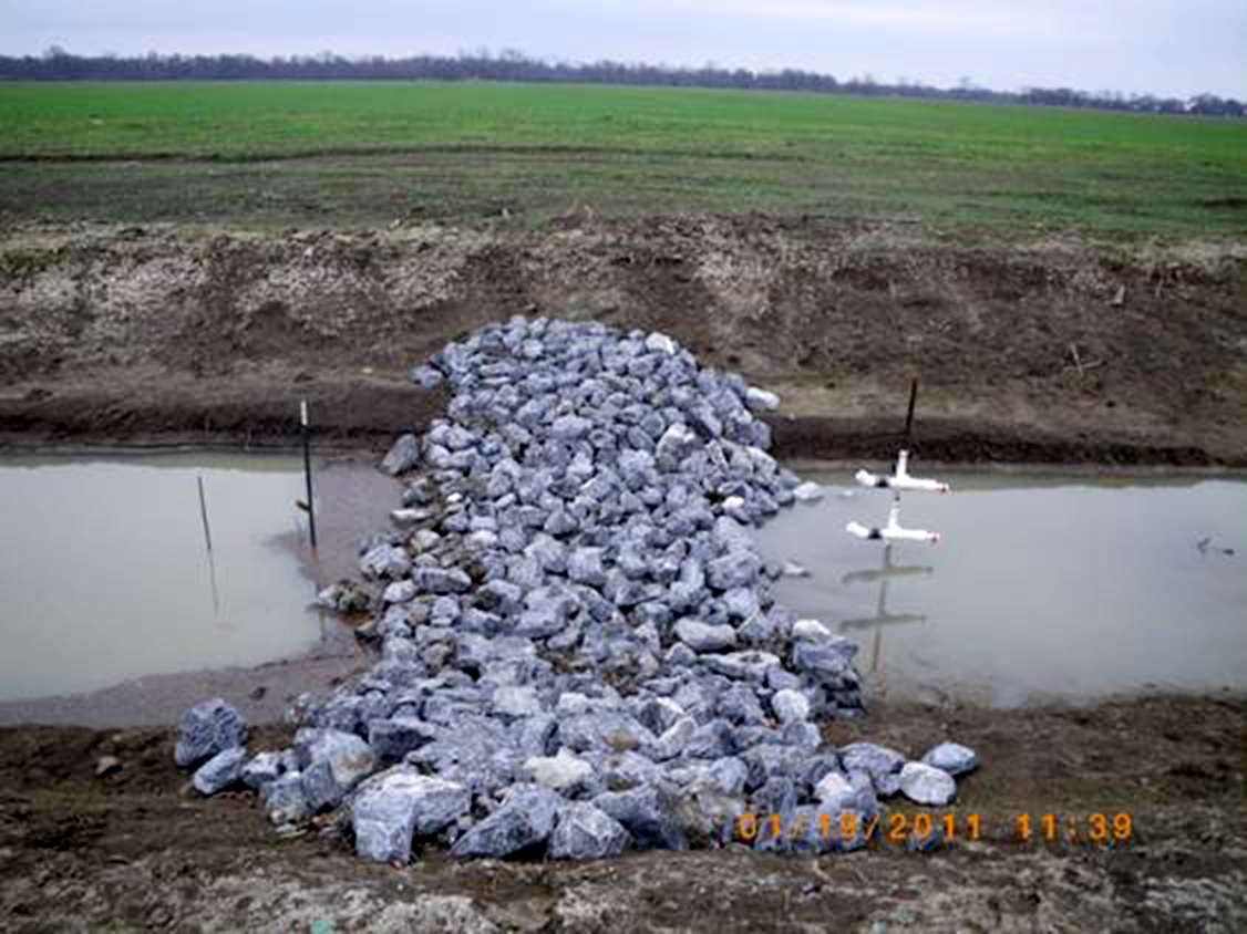 Low-grade weir made of riprap covering an earthen berm. The structure was being monitored for water-quality improvements on a working farm in the Mississippi Delta.