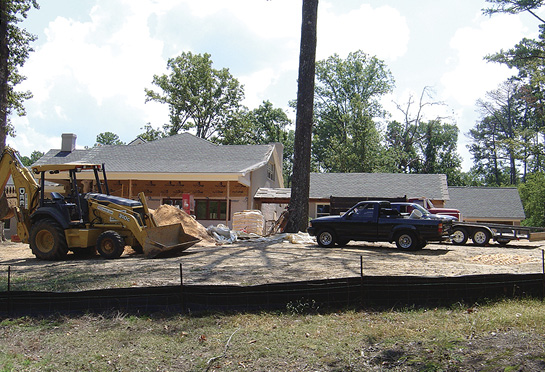 Trucks and heavy equipment are parked around a house that is under construction.