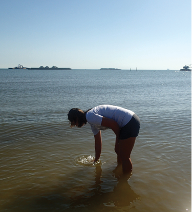 The researcher holds the jar upright into the water to let air bubbles escape.