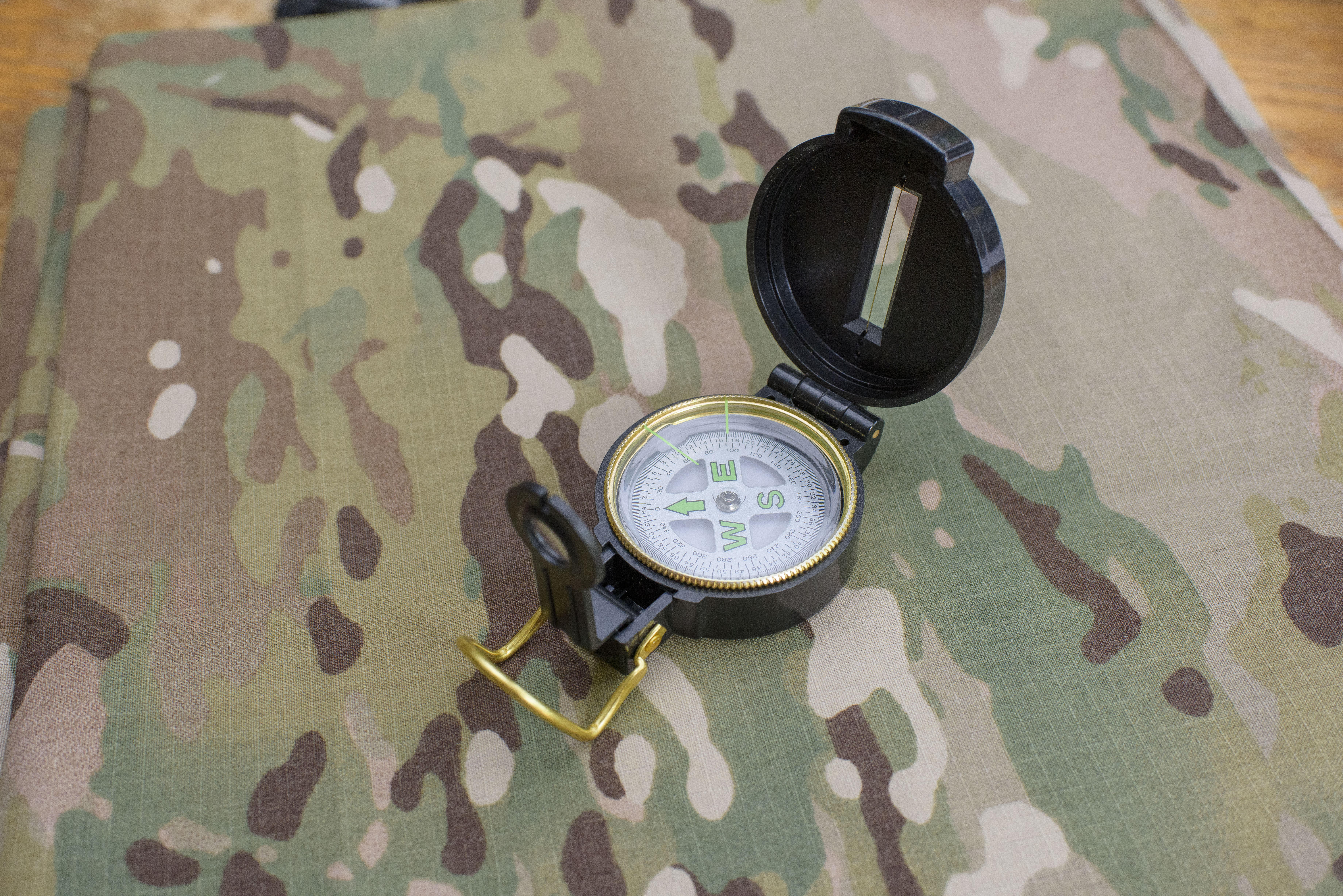 An open compass on a camouflage background.