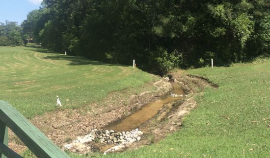 A ditch with water runs through a green golf course.