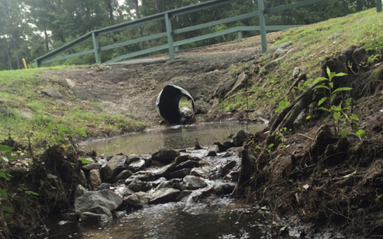 Water flows through a ditch and over rocks.