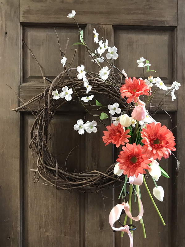 Completed grapevine wreath with pink and white flowers.