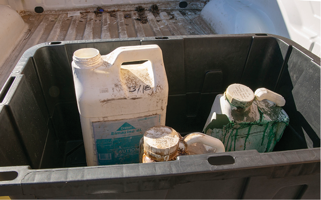 A large, plastic container holding smaller containers with signs of leaking.