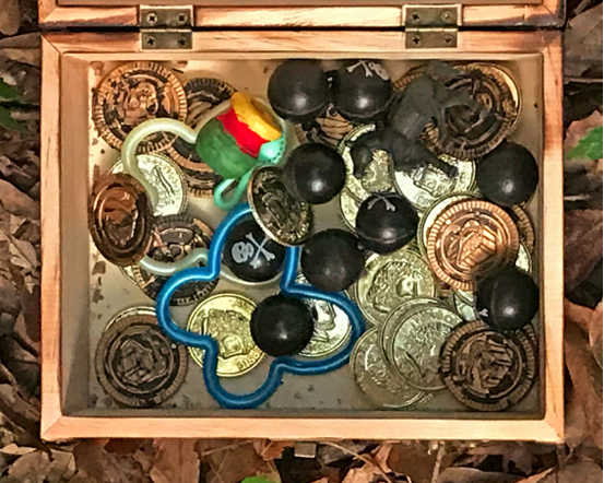 Opened wooden box filled with coins, buttons, and other tradable items.