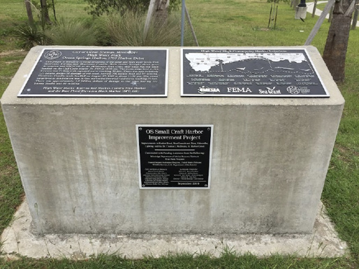 A large concrete block with plaques with information on the High Water Mark Initiative and the impacts of Hurricanes Camille and Katrina to the Mississippi Gulf Coast.