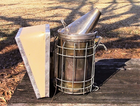 A metal cylindrical container with a conical opening on one end, and a large, wedge-shaped bellows.