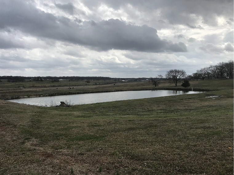 A rectangular body of water in a large, grassy field.