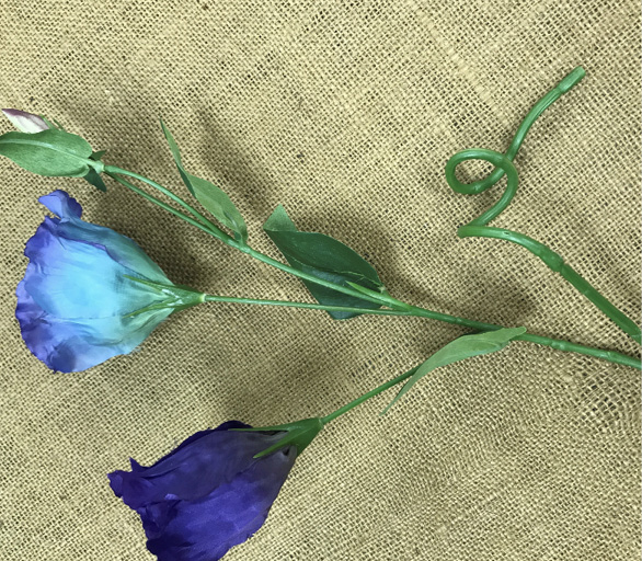 A medium piece of Eustoma with a curled stem helps fill out the wreath even more. This piece is being prepared for glue.