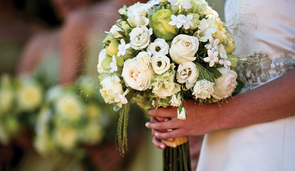 A bride holds a bouquet of white flowers.