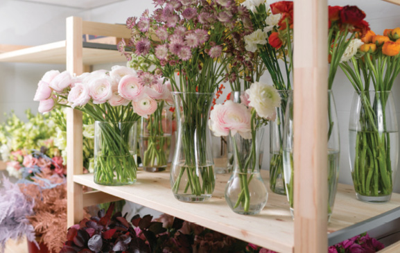 Shelves of flowers in vases.