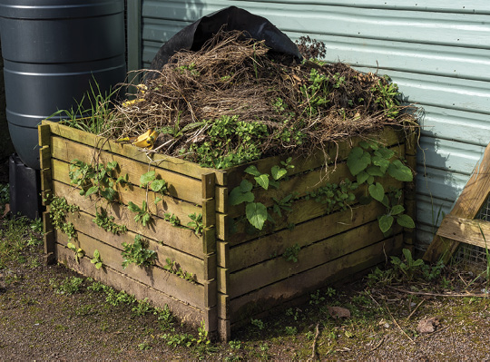 Wooden container overflowing with plant and other organic debris.