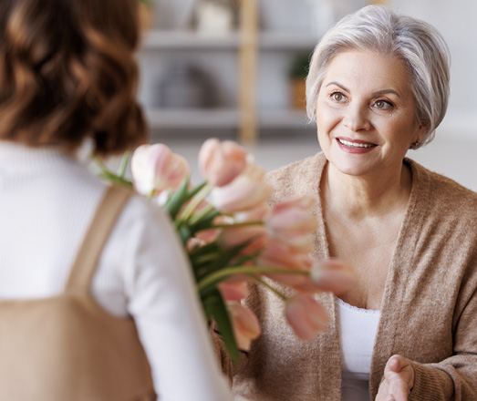 A person giving a bouquet of flowers to another person.