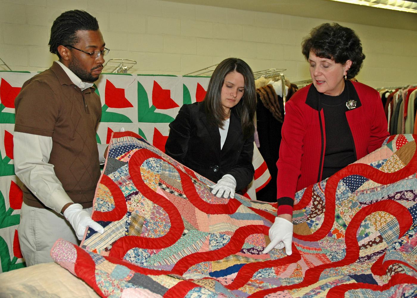 Mississippi State University students Parron Edwards (left), a junior from Lexington, and Shannon Sorro, a senior from Clarksville, Tenn., listen as Wanda Cheek, associate professor of human sciences, discusses the intricacies of quilts and their patterns.