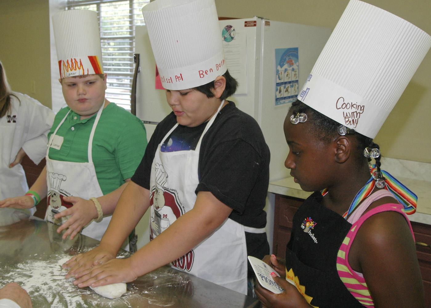 From left, Lamar Land, Ben Barker and Murritta Lane work as a team kneading dough to make bread. "Fun with Food" participants made many nutritious meals during their week at camp. (Photo by MSU Office of Ag Communications)