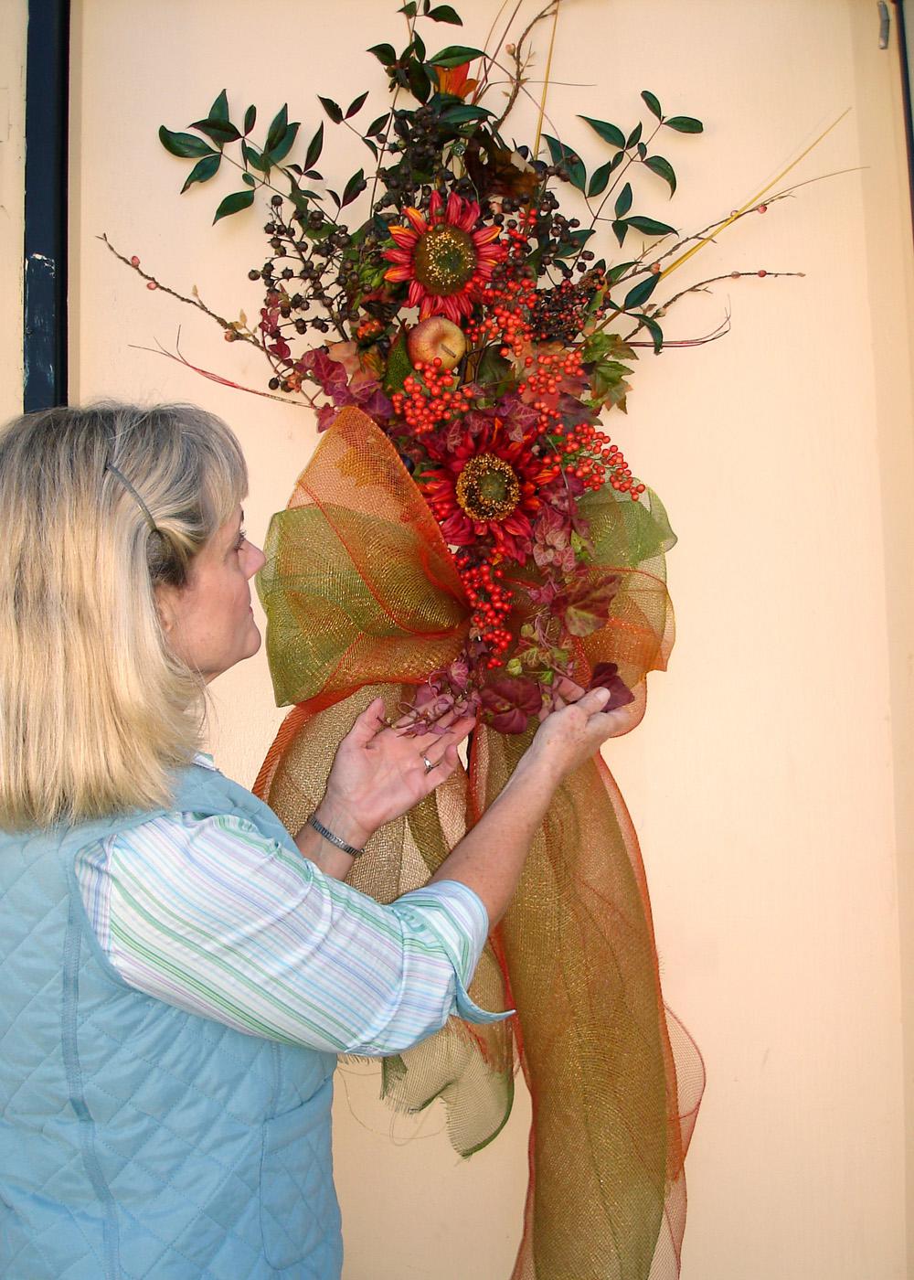 Create unique decorations and gifts for less using resources from gardens, fields and woods. Lelia Kelly puts the finishing touches on a door swag she made using crape myrtle seed pods, nandina foliage and berries, English ivy and bare branches, highlighted with silk sunflowers and other silk materials. (Photo by Vickie McGee)