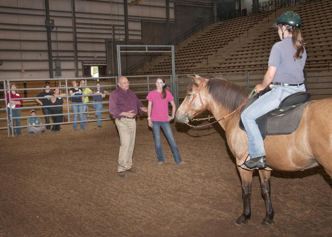 Anthony Busacca, a master's level instructor with the North American Riding for the Handicapped Association, teaches Hannah Miller, standing, and Natalie Clark Langston methods for effective and safe therapy sessions. (Photo by Scott Corey)